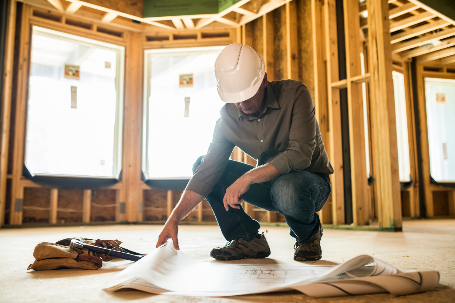 General contractor reviewing blueprints on a framed home